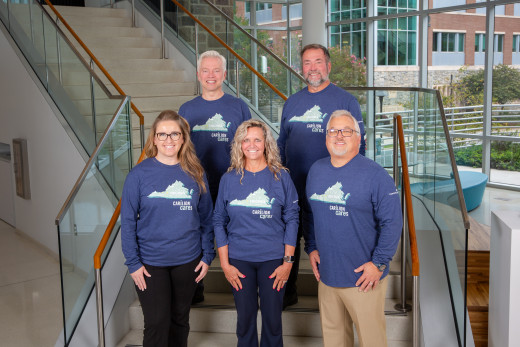 Five employees wearing the 2026 Carilion Cares, I Care t-shirts, smiling on a staircase