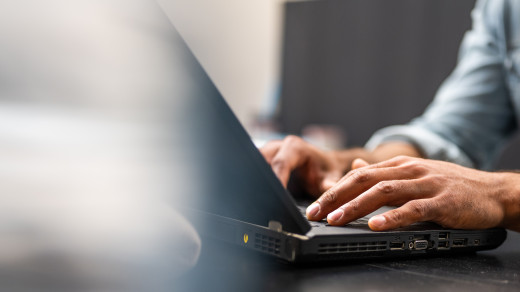 Hands typing on a laptop keyboard.