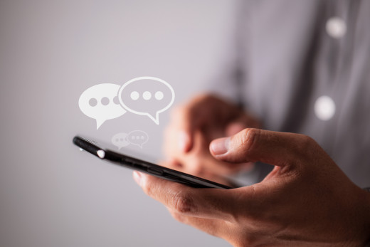 text bubbles above a phone that someone is typing on