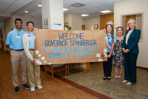 Gov. Abigail Spanberger poses with hospital volunteers holding a handmade welcome sign at CRBH